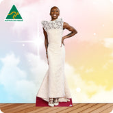 Woman wearing a white dress with lace details, standing on a wooden floor with a colorful background.